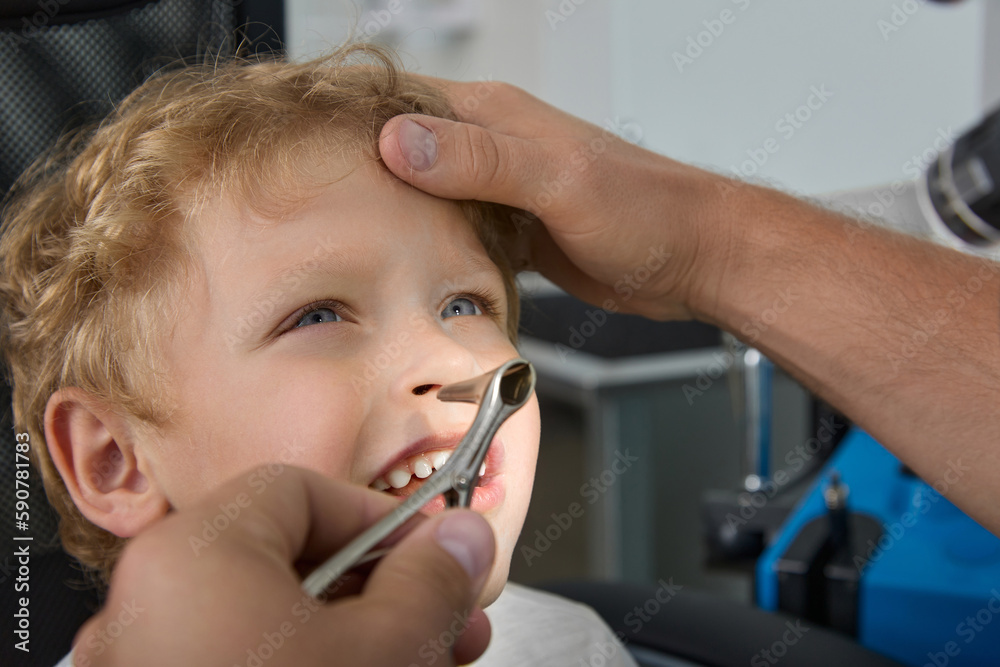 Doctor tilted the boy's head back to examine the nose using a nasal