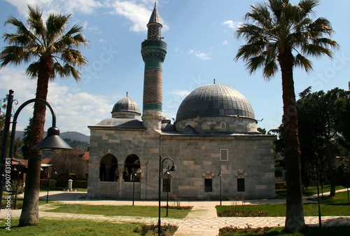 Photo of a view of the Yesil Camii mosque with a green minaret surrounded by tall palm trees in the historic part of Iznik, Turkey photo