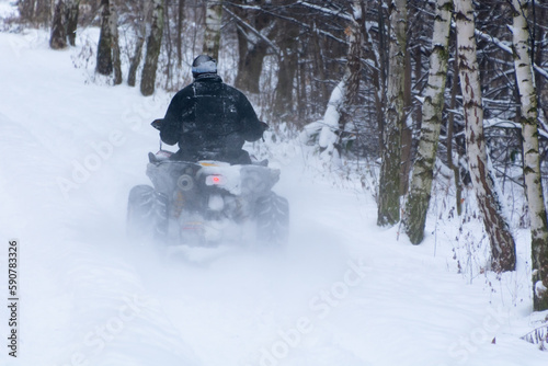 zima, człowiek na quadzie jadący leśną, zasypaną śniegiem drogą