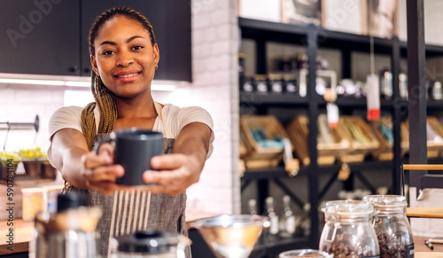 Portrait of african american barista woman small business owner working behind the counter bar and receive order from customer on coffee packaging and cup of coffee background in cafe or coffee shop