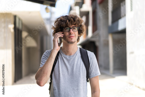 Portrait of smiling happy casual hipster handsome man with backpack relaxing using digital technology smartphone.Young man work call and talk with friend business team at city