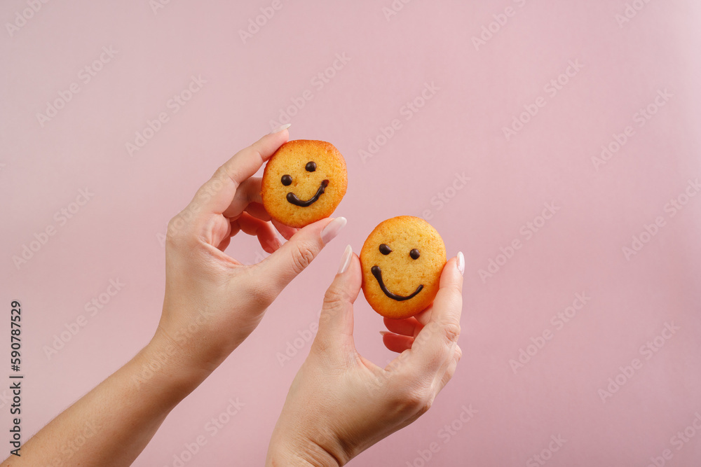 A young woman is holding a smiley cookie in her hands. Delicious and healthy dessert for kids. Gluten free products.