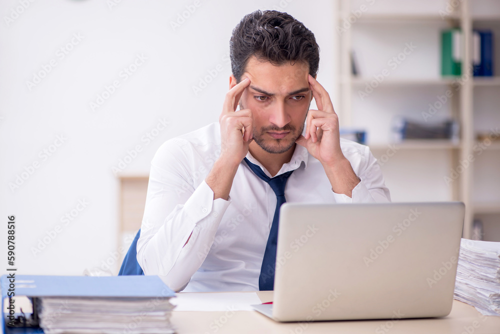 Young male employee and too much work in the office Young male employee and too much work in the office