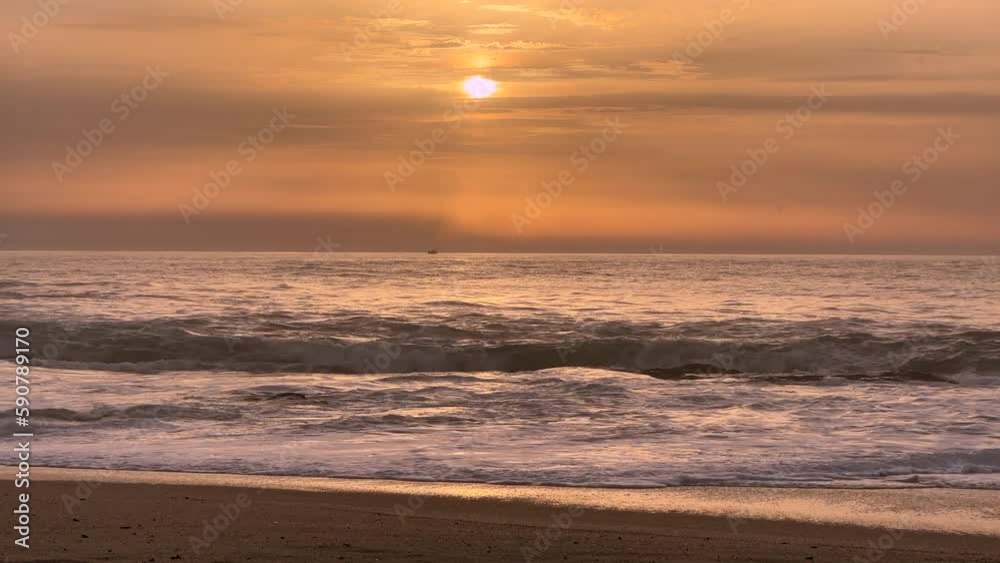 Beautiful calm, sunset over the ocean, with muted, pastel orange shades and small fishing boat bobbing on waves in distance. Beautiful calm, sunset over the ocean, with muted, pastel orange shades and small fishing boat bobbing on waves in distance.