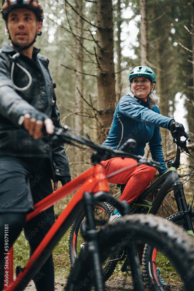 Mature woman mountain biking in the woods with a friend Mature woman mountain biking in the woods with a friend