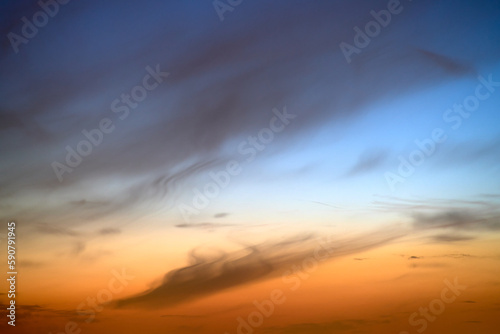 Sunset sky with red light of the setting sun. Evening clouds in the orange light of sunset rays