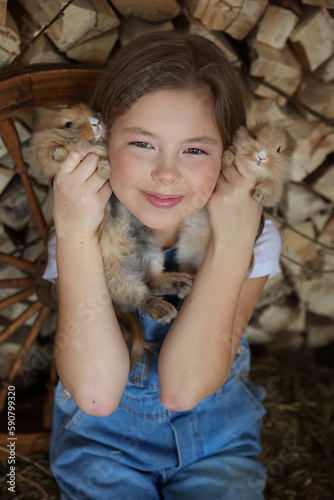 cute girl smiles and holds live rabbits in her hands. country style. easter content