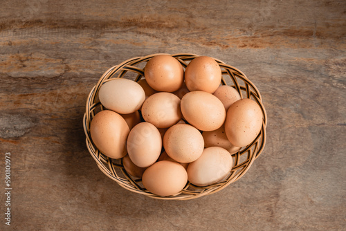 Fresh raw eggs in the basket on wooden table.