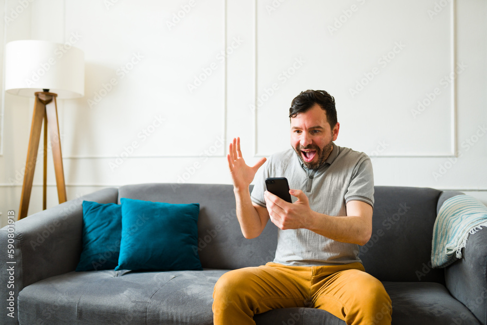 Surprised man celebrating getting good news texting Surprised man celebrating getting good news texting