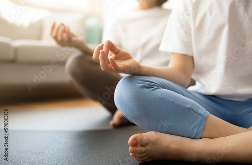 Teen european girl and millennial woman in sportswear sit in lotus position on mat, meditate, practice yoga
