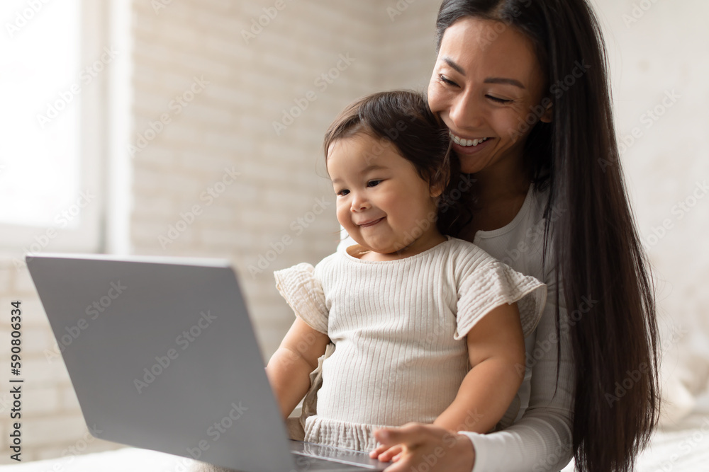Happy Asian Mom And Little Baby Daughter Using Laptop Indoor Happy Asian Mom And Little Baby Daughter Using Laptop Indoor