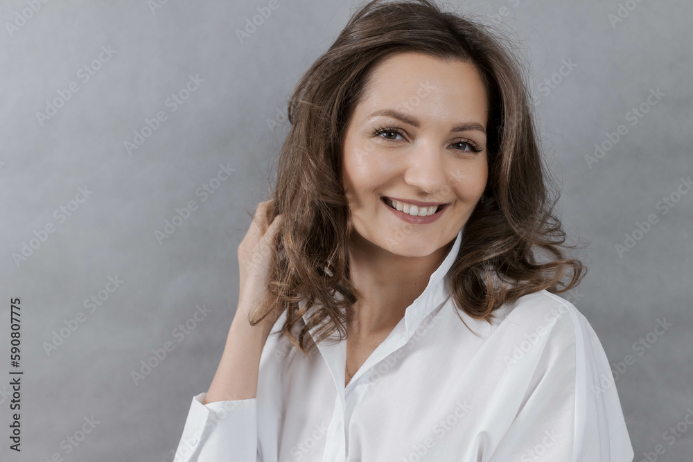 Close-up portrait of a happy smiling young woman holding her hair with her hand Close-up portrait of a happy smiling young woman holding her hair with her hand