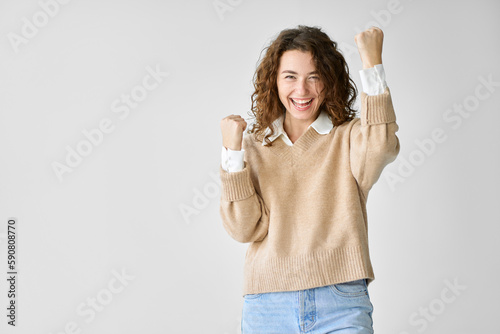 Young happy lucky overjoyed woman model student feeling excited winner raising fists in yes gesture celebrating great crazy win, rejoicing victory feeling joy standing isolated at white background.