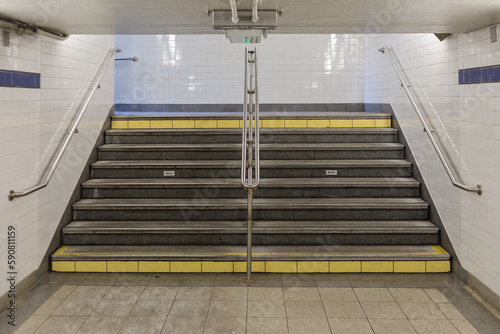 Subway stairs with hand rails, low ceilings and tiled walls