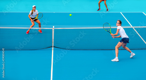 Tennis players play mixed doubles on blue hard courts on a bright sunny day © Павел Мещеряков