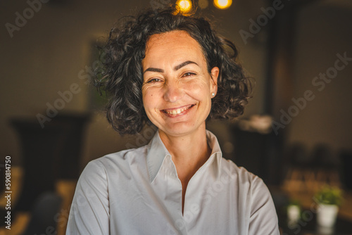 One woman mature caucasian female businesswoman entrepreneur stand at work or home real people copy space wear white shirt curly hair