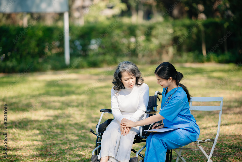 Elderly asian senior woman on wheelchair with Asian careful caregiver. Nursing home hospital garden Elderly asian senior woman on wheelchair with Asian careful caregiver. Nursing home hospital garden