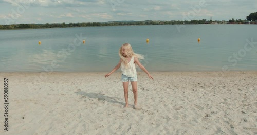 Charming little girl doing stretching exercises on the beach