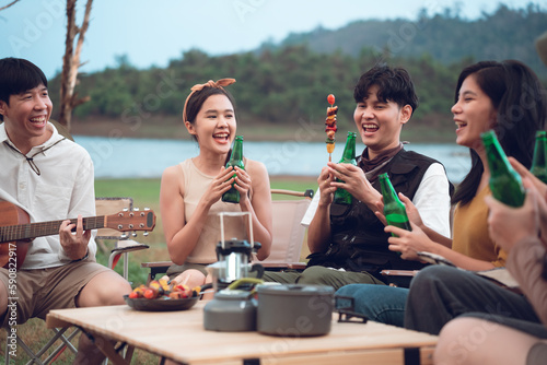 Group of diverse young asian people enjoy bbq and beer camping party in evening at campground, Outdoor lifestyle on vacation summer.