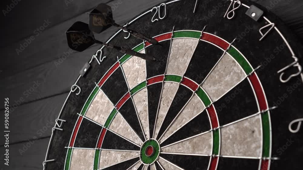 Three darts hit the dartboard. Lucky - one of the darts hits a triple twenty. The concept of winning and luck. Close-up, angled view