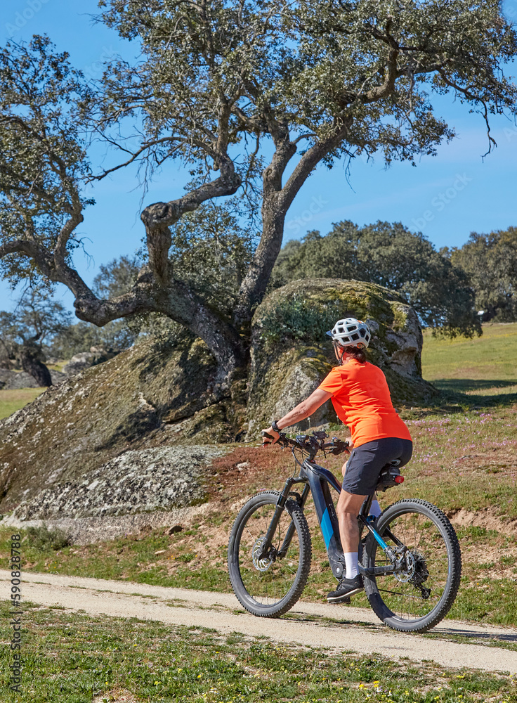 nice senior woman cyling with her electric mountain bike in a stone oak forest of the Extremadura department of Spain
