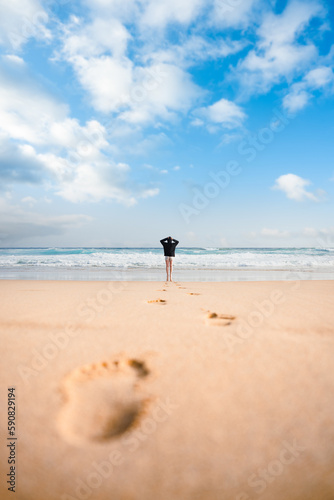 Obraz na płótnie Stunning view a girl walking on the Cofete beach with her footprints on the sand in the foreground. Fuerteventura, Canary Islands. w salonie
