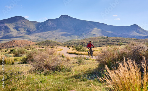 nice senior woman cycling with her electric mountain bike in the volcanic nature park of Cabo de Gata, Costa del Sol, Andalusia, Spain