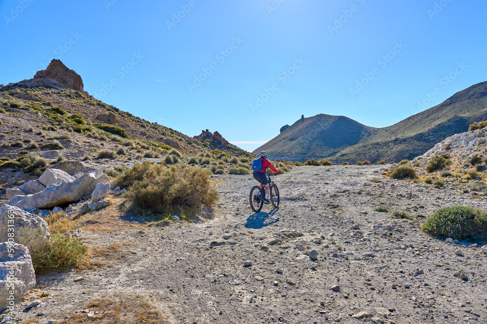 Fototapeta premium nice senior woman cycling with her electric mountain bike in the volcanic nature park of Cabo de Gata, Costa del Sol, Andalusia, Spain