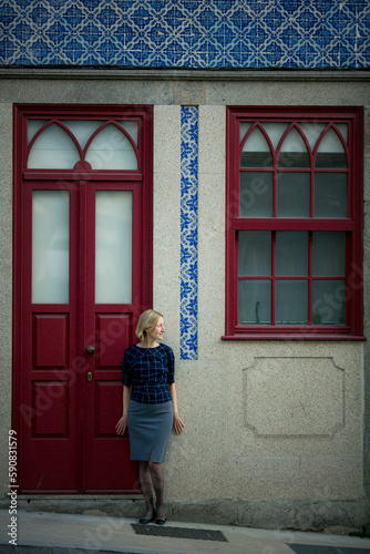 A woman stands outside a historic residential building in Porto, Portugal.