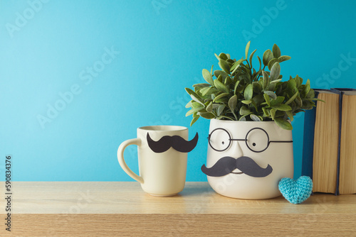 Happy Father's day concept with cute funny plant, coffee cup and heart shape on wooden table over blue background