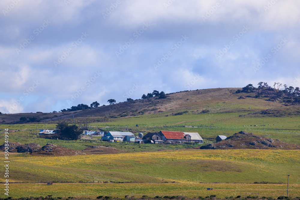 Historic farm and ranch buildings in rolling green hills on sunny day