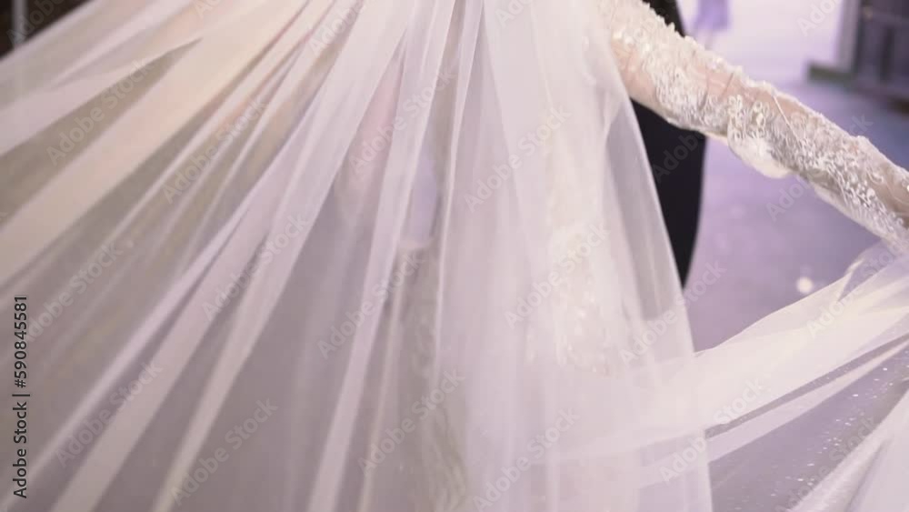 A bride in a long white wedding dress with veil and high-heeled shoes walks on a street. Wedding ceremony, reception. A bride in a long white wedding dress with veil and high-heeled shoes walks on a street. Wedding ceremony, reception.