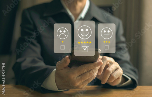 Businessman pressed the smile face emoticon on the virtual touch screen and give five star symbol to increase rating of products and services ,customer service and satisfaction survey concept.
