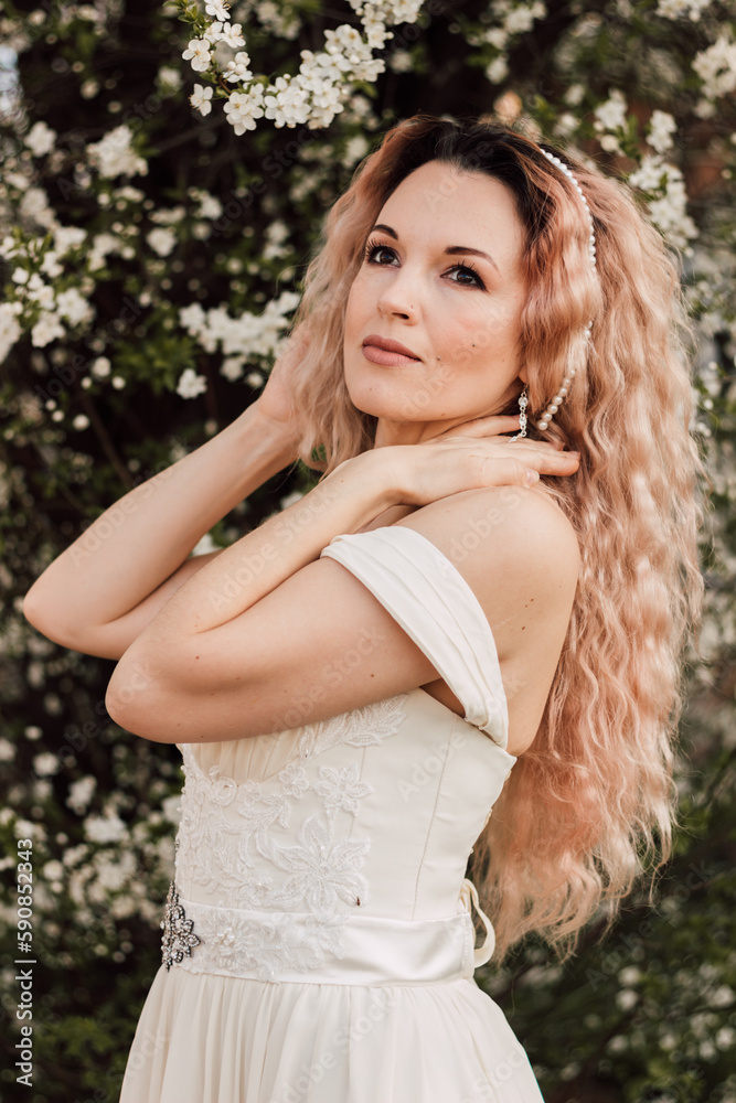 A beautiful woman in a spring garden near cherry blossoms. Flowering garden A beautiful woman in a spring garden near cherry blossoms. Flowering garden