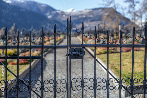 Wrought iron gate at the entrace of a graveyard with the backgound of the snow covered Alps