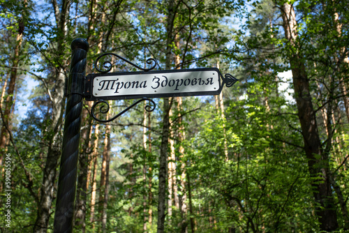 Blurred summer forest and plate with inscription on Rusian pathway of health in foreground close up