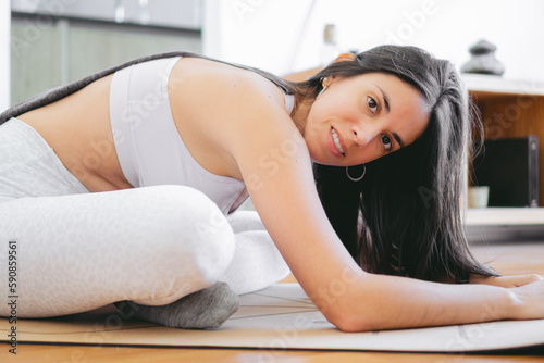 Young latin woman on a mat in the middle of a yoga session in sportswear looking at the camera.