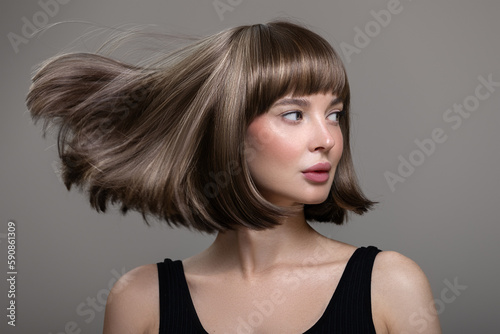 Portrait of beautiful fashion woman with bob hairstyle. Flying hairs up. Surf background