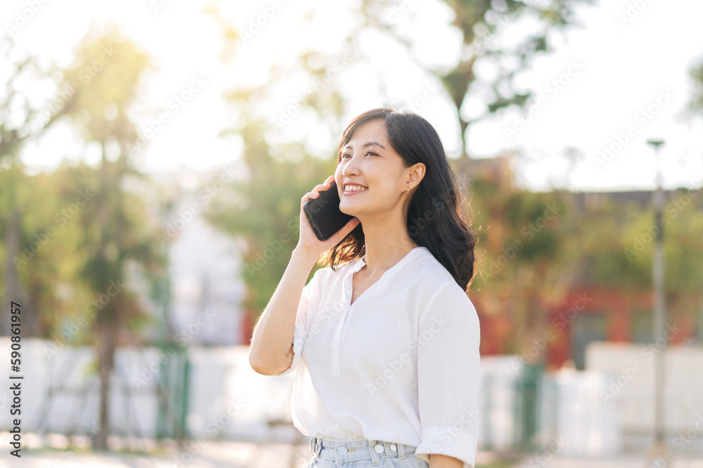 Portrait beautiful young asian woman with smart mobile phone around outdoor nature view in a sunny summer day Portrait beautiful young asian woman with smart mobile phone around outdoor nature view in a sunny summer day