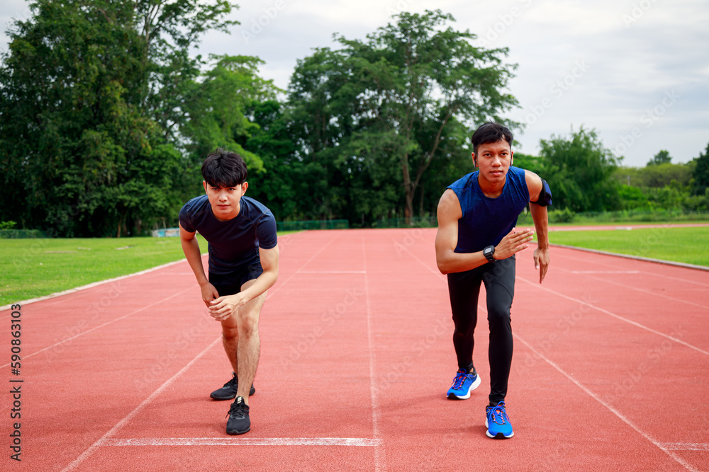 Two young Fit and confident Asian teenagers in starting position ready for running. Male athlete start a sprint