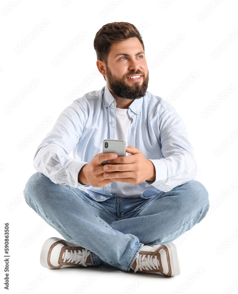 Young bearded man with mobile phone sitting on white background Young bearded man with mobile phone sitting on white background