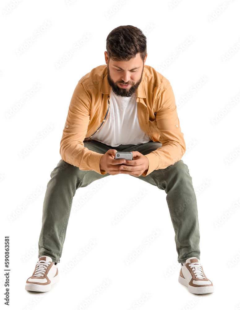Young bearded man using mobile phone in chair on white background Young bearded man using mobile phone in chair on white background