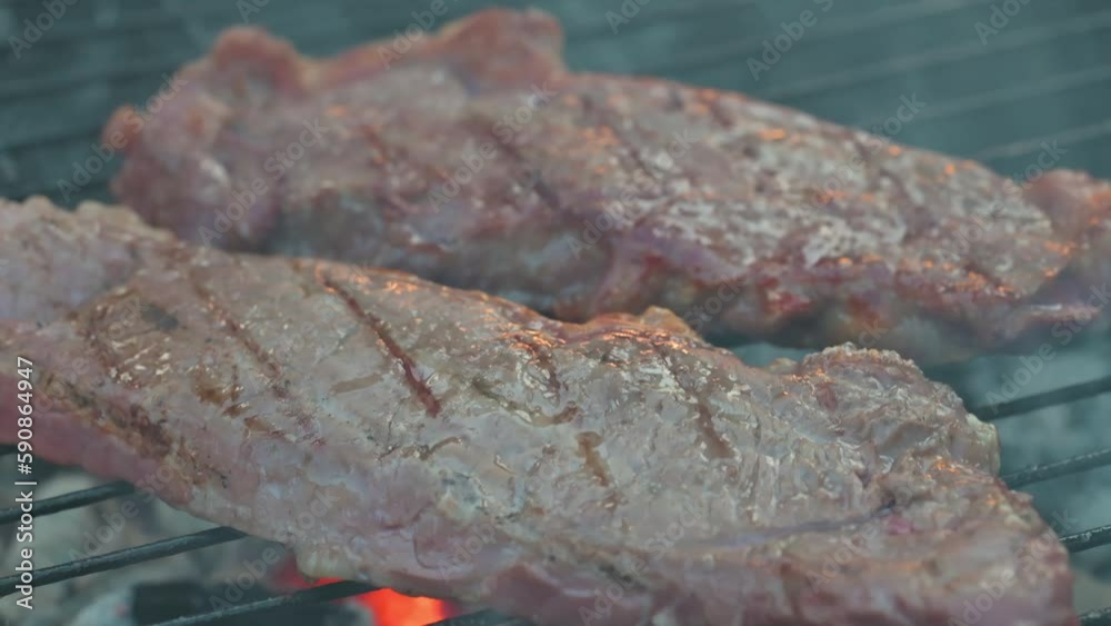 Man cooking and rotating beaf steakes on grill. 4k video footage in slow motion Man cooking and rotating beaf steakes on grill. 4k video footage in slow motion