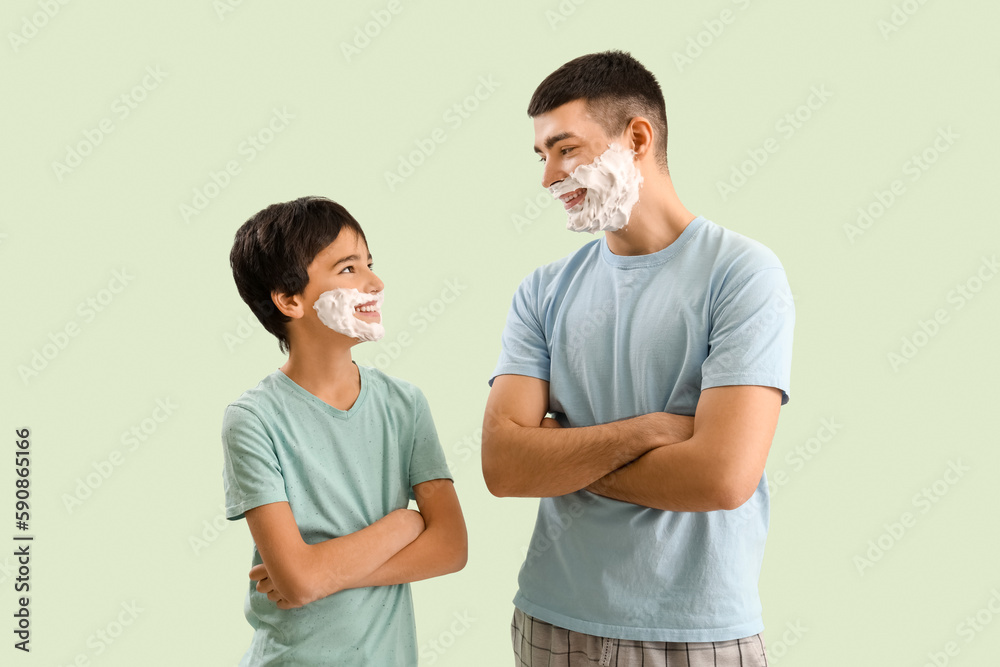 Man and his little son with shaving foam on faces against light color background Man and his little son with shaving foam on faces against light color background