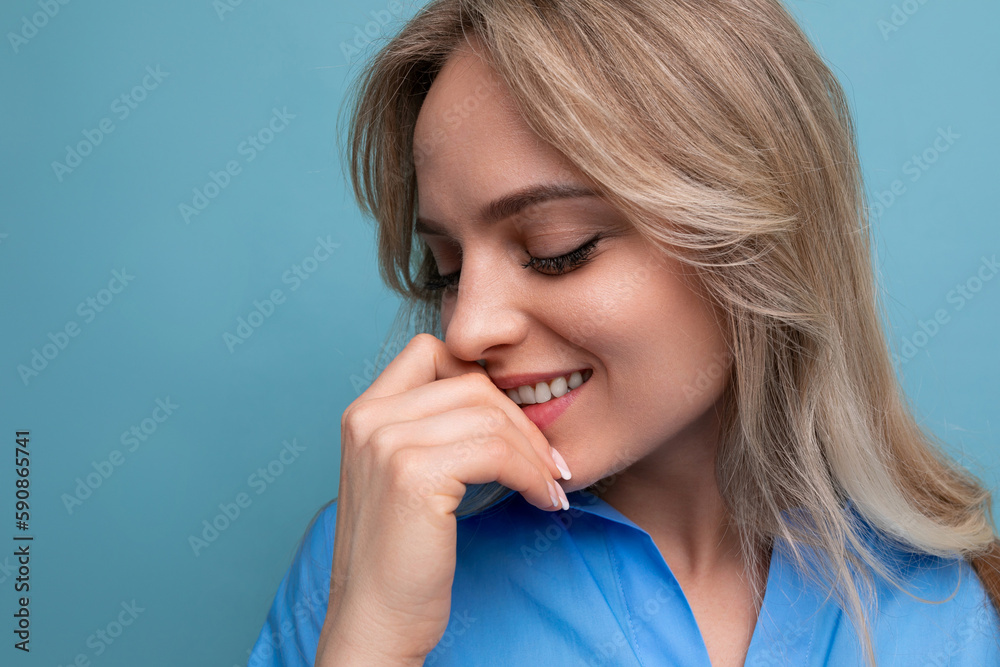 close-up of shy cute casual young woman looking away against bright blue background close-up of shy cute casual young woman looking away against bright blue background