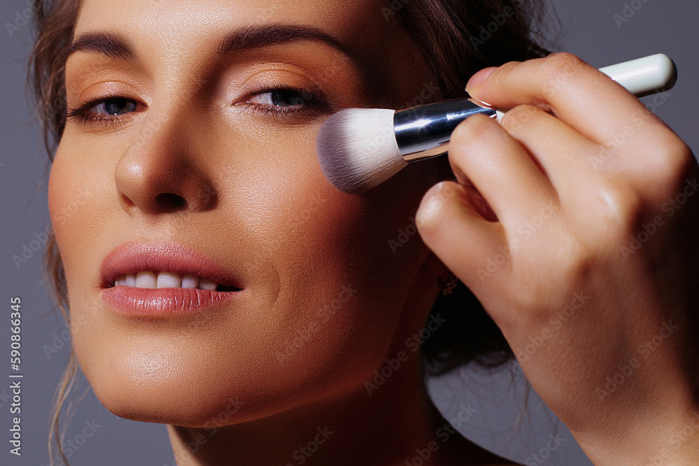 Applying makeup with brush to face of beautiful adult woman Applying makeup with brush to face of beautiful adult woman