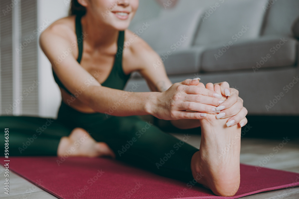 Full body cropped young strong athletic fitness trainer instructor woman in green tracksuit train do stretch lunge exercise sit on floor touch foot at home gym indoor Workout sport motivation concept. Full body cropped young strong athletic fitness trainer instructor woman in green tracksuit train do stretch lunge exercise sit on floor touch foot at home gym indoor Workout sport motivation concept.