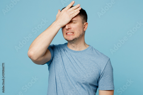 Young sad caucasian displeased man wears casual t-shirt put hand on face facepalm epic fail mistaken omg gesture isolated on plain pastel light blue cyan background studio portrait. Lifestyle concept.