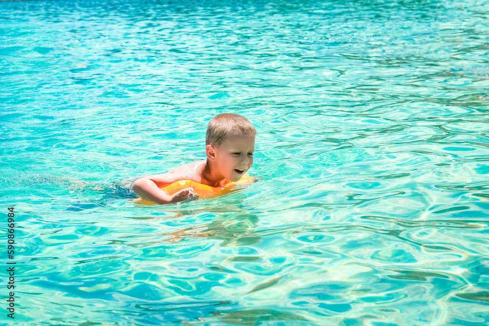 A Happy child swims near the shore in flippers in the sea of travel