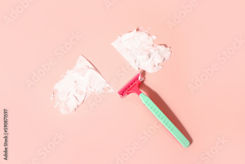 Safety razor and shaving foam on pink background photo